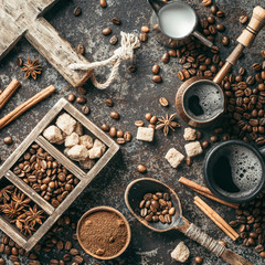 Coffee cup, sugar, milk and coffee beans on dark background.