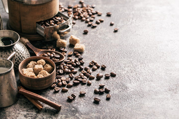 Coffee with coffee grinder and coffee beans on dark textured background.