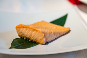 A piece of salmon steamed lies on a sheet on a plate