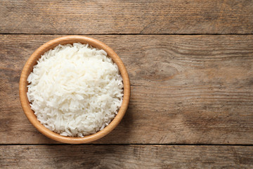 Fototapeta na wymiar Bowl of delicious rice on wooden table, top view with space for text