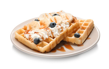 Plate with yummy waffles, whipped cream, blueberries and banana on white background