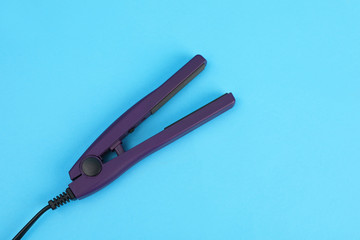 Modern hair iron for straightening on color background, top view