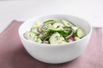 Delicious fresh cucumber onion salad in bowl served on table