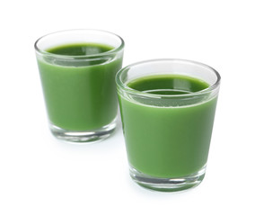 Fresh wheat grass juice in glasses on white background