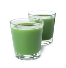 Fresh wheat grass juice in glasses on white background
