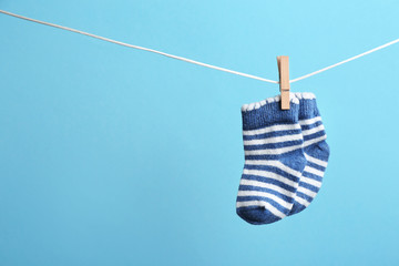 Small socks hanging on washing line against color background, space for text. Baby accessories