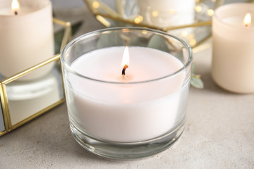 Burning aromatic candle in holder on table