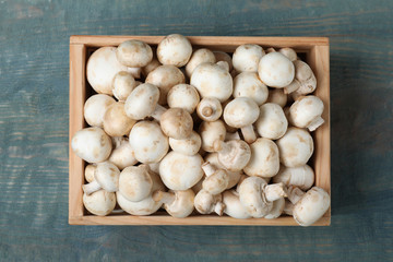 Wooden crate full of fresh raw mushrooms on table, top view