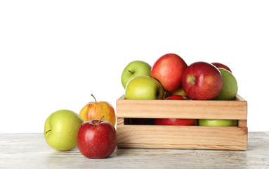 Wooden crate full of fresh juicy apples on table against white background