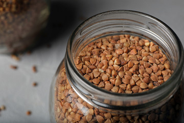 Uncooked buckwheat in glass jar on table, closeup