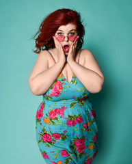 Amazed plus-size lady overweight woman in sunglasses and colorful sundress with her hands on her...
