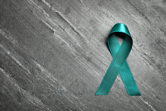 Teal ribbon on grey background, top view. Space for text