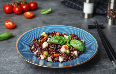 Plate of brown rice with vegetables on grey table