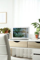 Houseplants and laptop on table in office interior