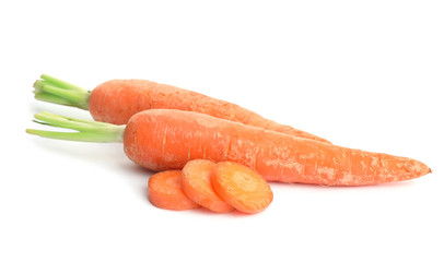 Whole and sliced ripe carrots on white background