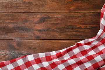 Checkered picnic blanket on wooden background, top view. Space for text