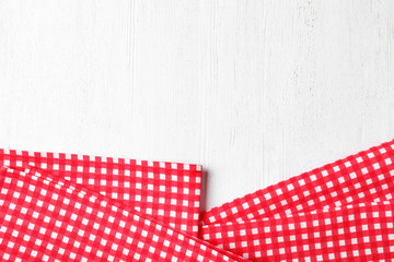 Checkered picnic napkins on wooden background, top view. Space for text