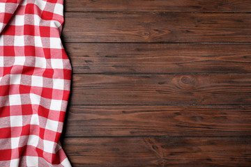 Checkered picnic blanket on wooden background, top view. Space for text