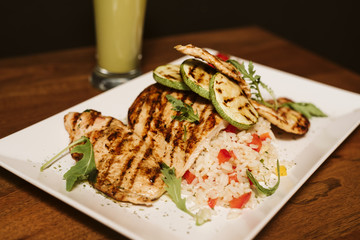 Grilled chicken with rice and vegetables by the glass of juice