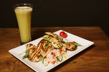 Grilled chicken with rice and vegetables by the glass of juice