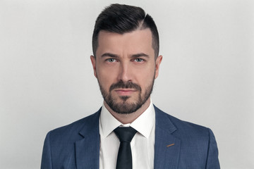 Closeup portrait of a confident business man dressed in suit isolated over gray background