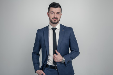 Portrait of a charming mature business man dressed in suit posing while standing and looking at camera isolated over gray background