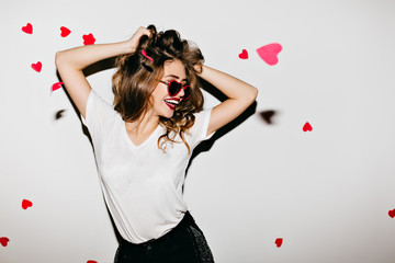Slim european woman in glamorous sunglasses laughing on white background. Photo of good-looking...