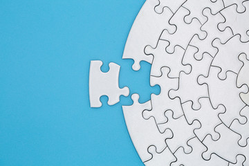 Unfinished white jigsaw puzzle pieces on blue background, The last piece of jigsaw puzzle, Copy space. - obrazy, fototapety, plakaty