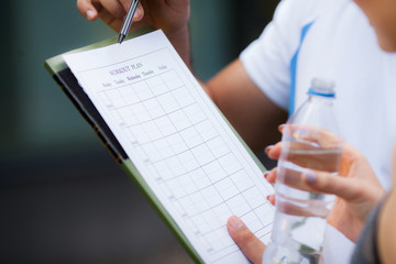 Fitness plan. Sports trainer amounts to workout plan close-up