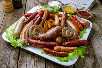 assorted sausages with sauces on plate on wooden background