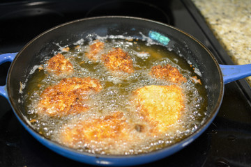 Frying fish in cooking oil on a stovetop 