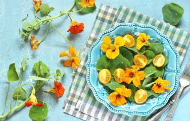salad with nasturtium leaves and flowers of the plant. bright summer salad with edible yellow flowers and yellow tomatoes with egg. top view.