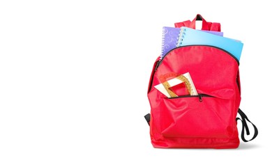 Colorful school supplies in backpack on white
