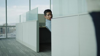 Slow motion of businessman in cubicle staring at businesswoman passing in office / Pleasant Grove, Utah, United States