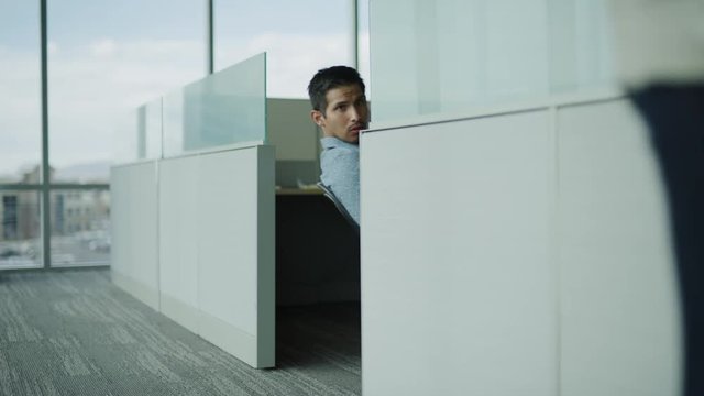 Slow motion of businessman in cubicle staring at businesswoman passing in office / Pleasant Grove, Utah, United States