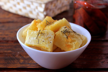 boiled and fried cassava (mandioca) in ceramic bowl on rustic wooden table