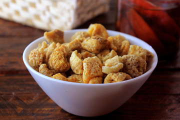 pork rinds fried in ceramic bowl on rustic wooden table in restaurant