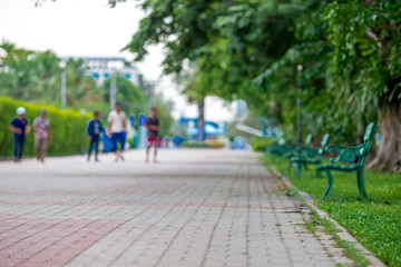 The blurred background of the chair, the seat in the park, among the green trees, has a pleasant shade during the break.