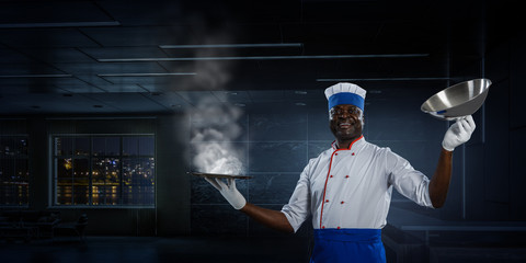 Naklejka premium Black man wearing an apron and cooking in action. Mixed media