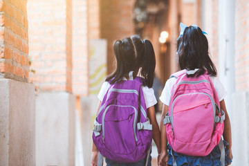 Back to school. Two cute asian child girls with school bag holding hand and walk together in the school