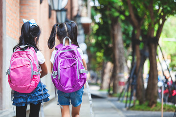 Back to school. Two cute asian child girls with school bag holding hand and walk together in the school