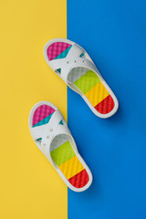 Colorful shoes for women on blue and yellow background. The concept of a holiday by the sea. Flat lay.