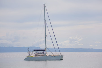 Catamaran sail boat at the coast line anchoring, in a luxury lifestyle summer sunny day photo