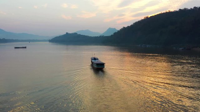 View from above, stunning aerial view of a tourists boat sailing along the Mekong river during a beautiful sunset. Luang Prabang, Laos.