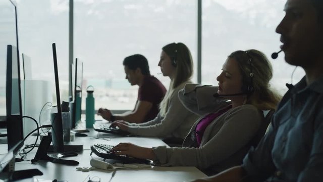 Tired customer service representative rubbing neck and removing headset in call center / Pleasant Grove, Utah, United States