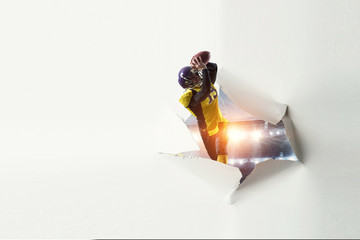 Paper breakthrough hole effect and football player. Mixed media