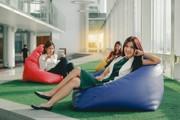 Group of three young using smartphone together, new style of workspace, relax scene of people in modern office.