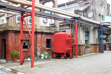 Fototapeta na wymiar Red steel tank in front of old brick house