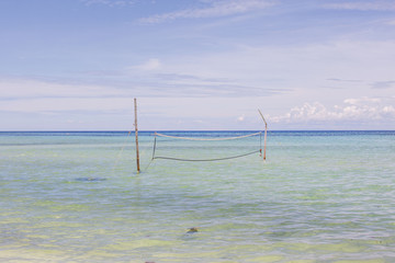 beach volleyball net at the white beach in high tide flooded on a sunny summer day, no people relaxing vacation scene