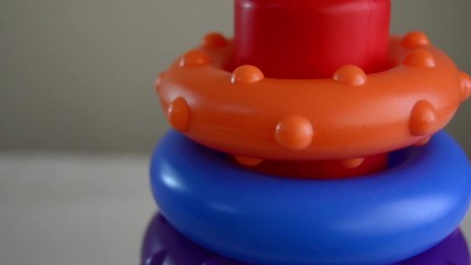 educational toy close up tilt up shot of colorful diferent sized rings on the stand